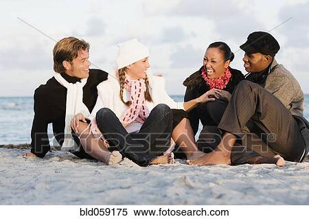 Multi-ethnic couples sitting on beach View Large Photo Image Stock Photography - Multi-ethnic couples sitting on beach. Fotosearch