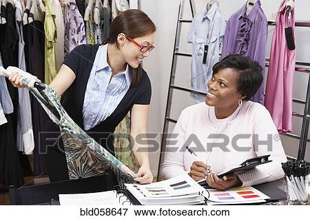 Stock Photo - Multi-ethnic fashion designers smiling at each other. Fotosearch