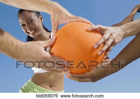 Multi-ethnic friends grabbing volleyball View Large Photo Image Stock Photo - Multi-ethnic friends grabbing volleyball. Fotosearch