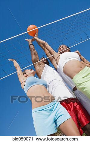 Stock Image - Multi-ethnic friends playing volleyball. Fotosearch