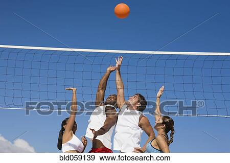 Stock Photo - Multi-ethnic friends playing volleyball. Fotosearch