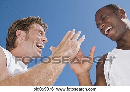 Stock Photograph - Multi-ethnic men high-fiving. Fotosearch