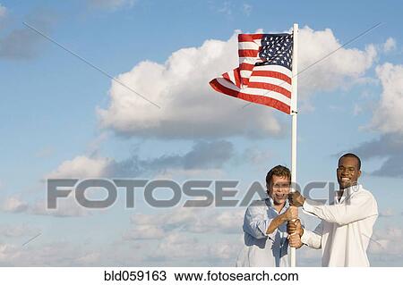 Stock Image - Multi-ethnic men holding American flag. Fotosearch