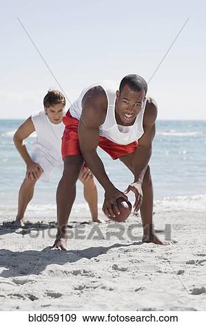 Stock Photo - Multi-ethnic men playing football. Fotosearch