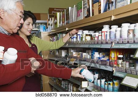 Stock Image - Senior Asian man shopping for natural medicine. Fotosearch