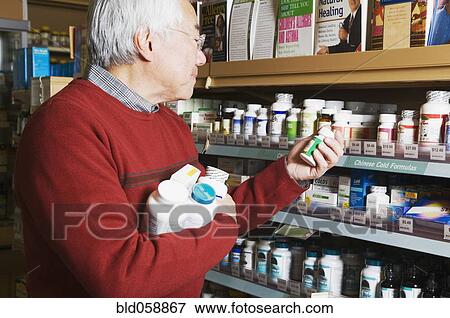 Stock Photo - Senior Asian man shopping for natural medicine. Fotosearch