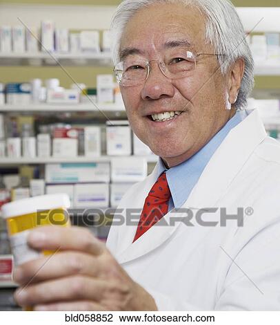 Senior Asian pharmacist holding medication bottle View Large Photo Image Stock Image - Senior Asian pharmacist holding medication bottle. Fotosearch