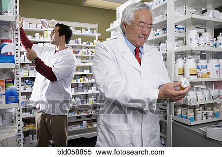 Stock Photography - Senior Asian pharmacist reading medication. Fotosearch