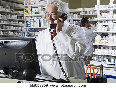 Senior Asian pharmacist talking on telephone View Large Photo Image Stock Photo - Senior Asian pharmacist talking on telephone. Fotosearch