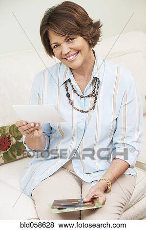Stock Photo - Senior Hispanic woman looking at photographs. Fotosearch
