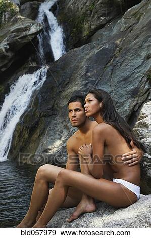 Stock Photo - Topless Hispanic couple next to waterfall. Fotosearch