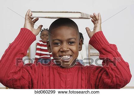 African boy holding book on head View Large Photo Image Stock Photo - African boy holding book on head. Fotosearch
