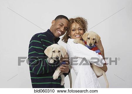 Stock Image - African couple holding puppies. Fotosearch