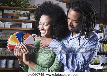 Stock Photography - African couple looking at paint swatches. Fotosearch