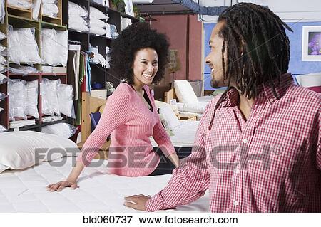 Stock Photo - African couple shopping for beds. Fotosearch