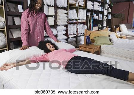 Stock Photography - African couple shopping for beds. Fotosearch