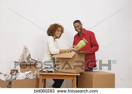 Stock Image - African couple unpacking moving boxes. Fotosearch