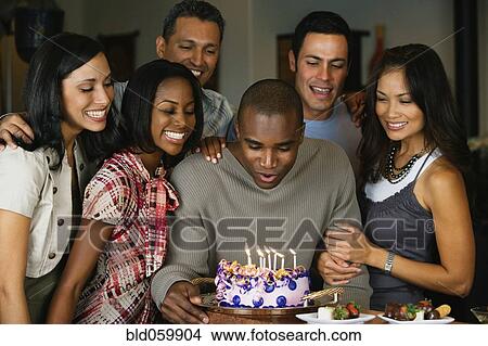 Picture - African man celebrating birthday with multi-ethnic friends. Fotosearch