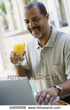 Stock Photograph - African man looking at laptop. Fotosearch