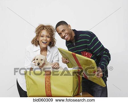 Stock Photo - African man surprising girlfriend with puppy. Fotosearch
