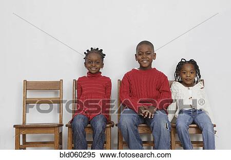Stock Photography - African siblings sitting in chairs. Fotosearch