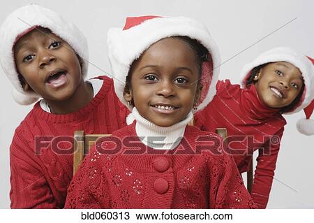 Stock Image - African siblings wearing Santa Claus hats. Fotosearch