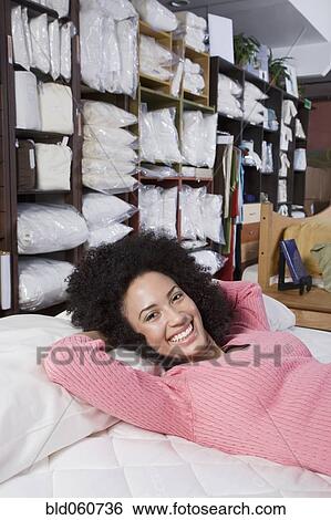 Stock Photograph - African woman laying on bed in store. Fotosearch