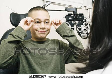 Stock Photo - Asian boy trying on eyeglasses. Fotosearch