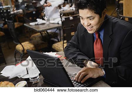 Picture - Asian businessman typing on laptop. Fotosearch