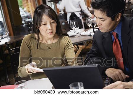 Stock Photo - Asian businesspeople looking at paperwork. Fotosearch