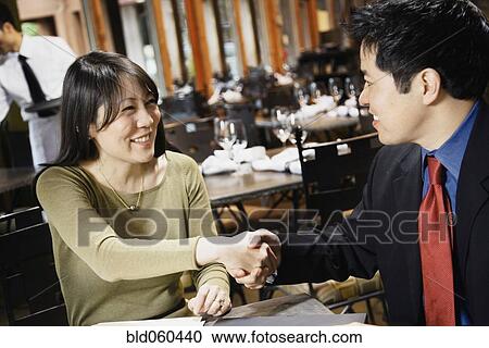 Stock Image - Asian businesspeople shaking hands. Fotosearch