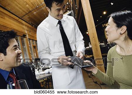 Stock Photography - Asian couple paying restaurant bill. Fotosearch