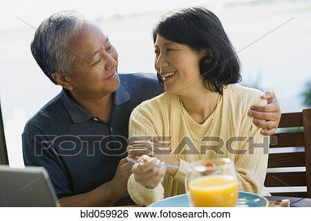 Stock Photograph - Asian couple smiling at each other. Fotosearch