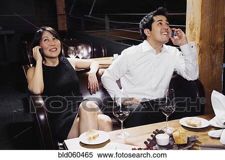 Stock Photography - Asian couple talking on cell phones. Fotosearch