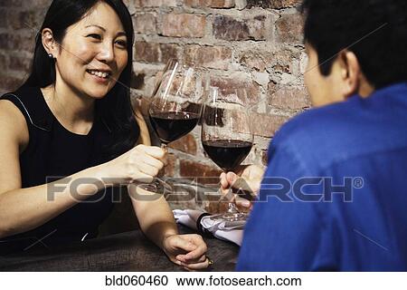 Stock Image - Asian couple toasting with wine. Fotosearch