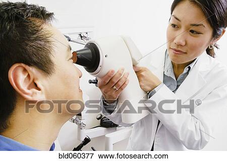 Stock Photo - Asian female optometrist examining patient. Fotosearch