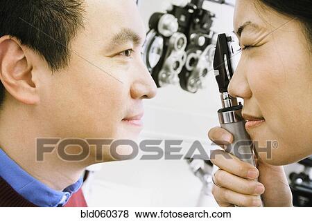 Stock Photo - Asian female optometrist examining patient. Fotosearch