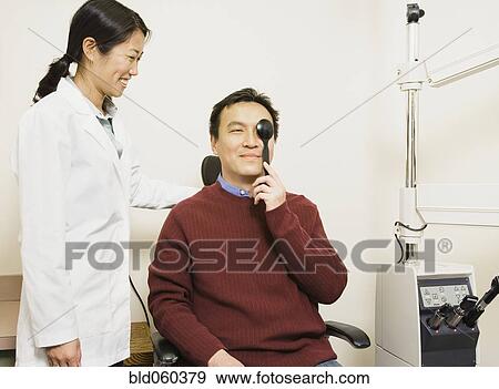 Stock Photo - Asian female optometrist examining patient. Fotosearch