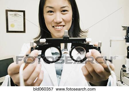 Stock Photo - Asian female optometrist holding equipment. Fotosearch