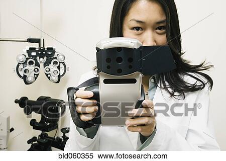 Stock Photography - Asian female optometrist holding equipment. Fotosearch