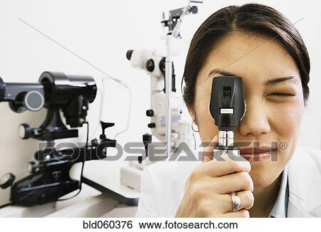 Asian female optometrist looking through equipment View Large Photo Image Stock Photograph - Asian female optometrist looking through equipment. Fotosearch
