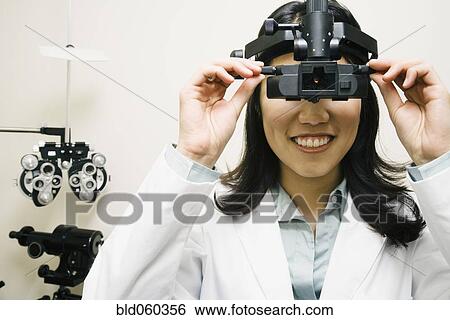 Asian female optometrist wearing examination equipment View Large Photo Image Stock Photograph - Asian female optometrist wearing examination equipment. Fotosearch