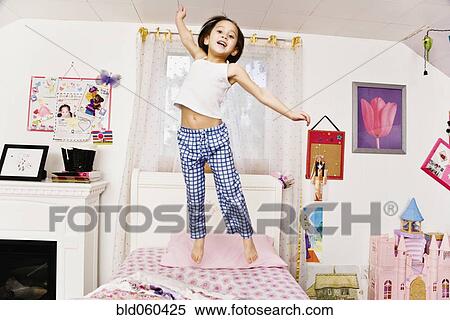 Stock Photography - Asian girl jumping on bed. Fotosearch