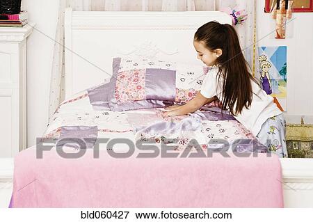 Stock Photo - Asian girl making bed. Fotosearch