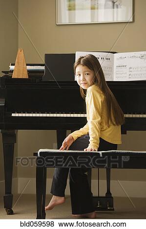 Stock Photo - Asian girl sitting at piano. Fotosearch