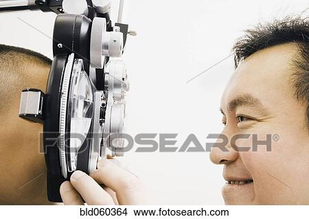 Asian male optometrist examining patient View Large Photo Image Picture - Asian male optometrist examining patient. Fotosearch