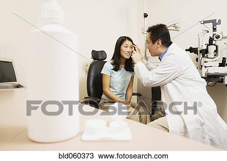 Asian male optometrist examining patient View Large Photo Image Stock Image - Asian male optometrist examining patient. Fotosearch