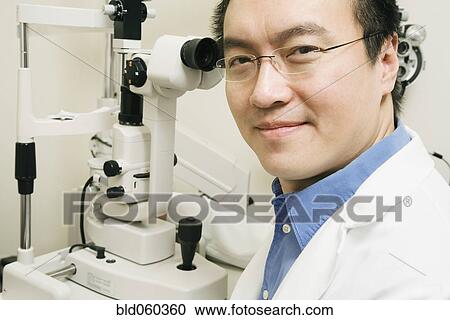 Stock Image - Asian male optometrist with equipment. Fotosearch
