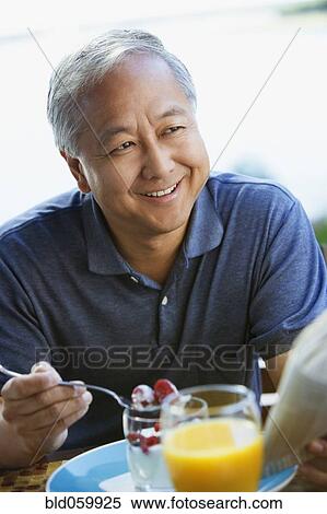 Stock Photography - Asian man eating breakfast. Fotosearch