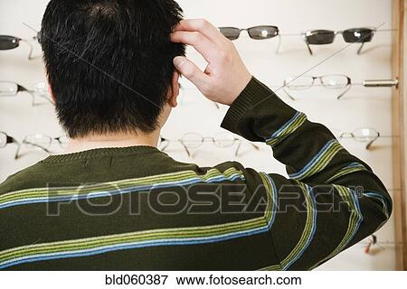 Stock Photo - Asian man shopping for eyeglasses. Fotosearch